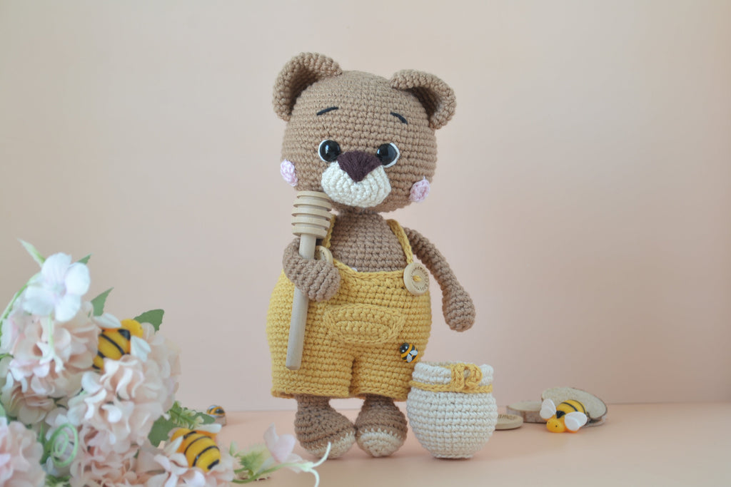 Honilo der Honigbär mit Löffel in der Hand und Honigfass daneben, Blumen, Bienen und Holz