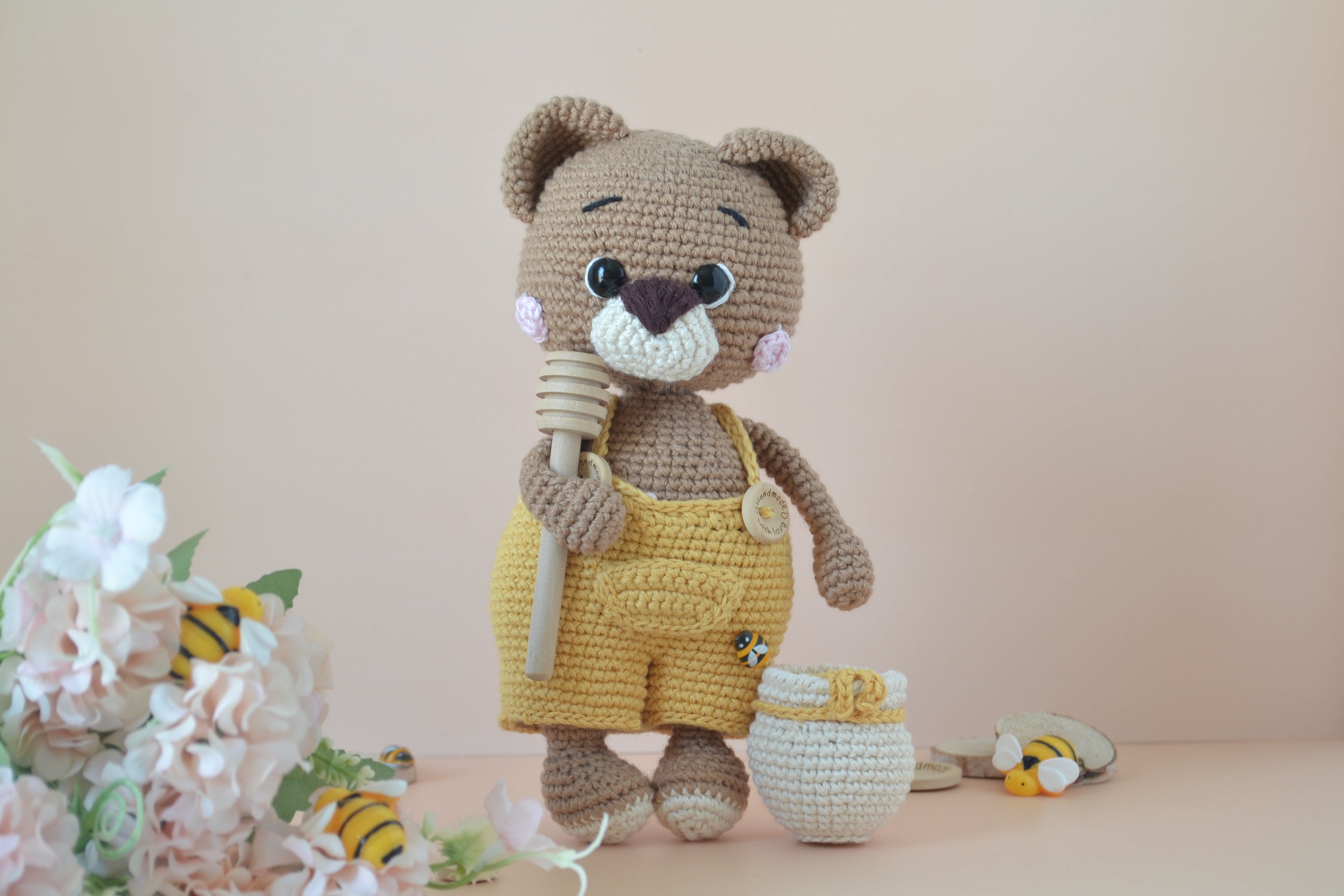Honilo der Honigbär mit Löffel in der Hand und Honigfass daneben, Blumen, Bienen und Holz